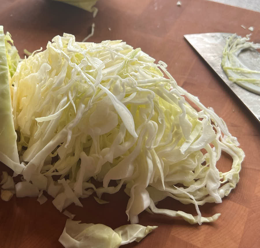 Thinly sliced green cabbage on a cutting board