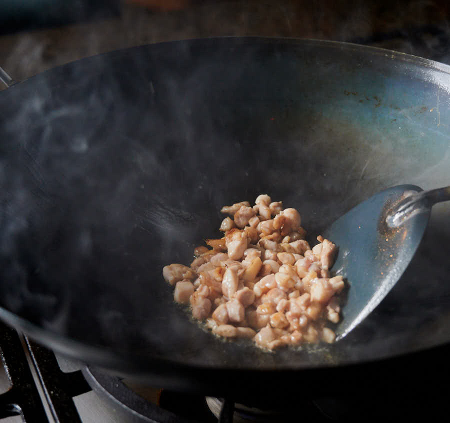 Small pieces of chicken in a smoky wok