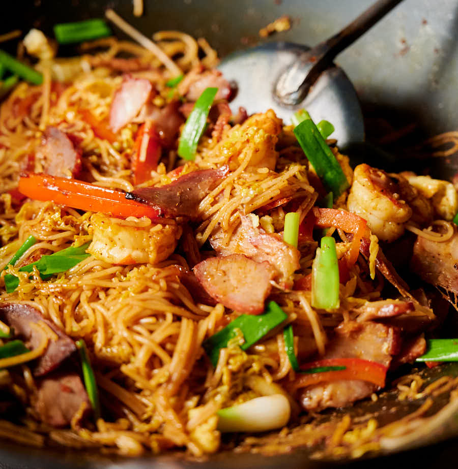 Singapore noodles in a wok with a chuan.