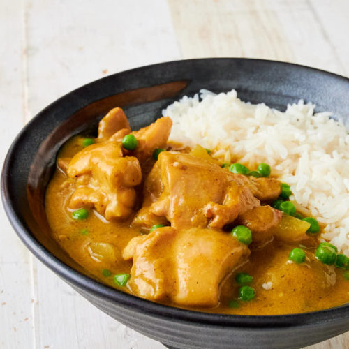 Cropped view of Chinese chicken curry in a bowl with a side of rice