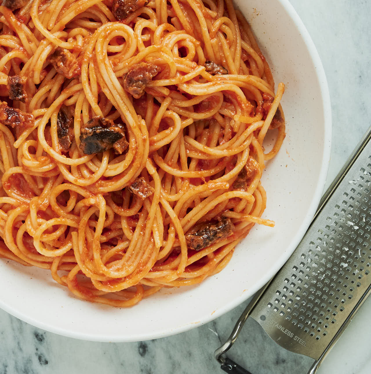 Bowl of spaghetti all'amatriciana and microplane grater