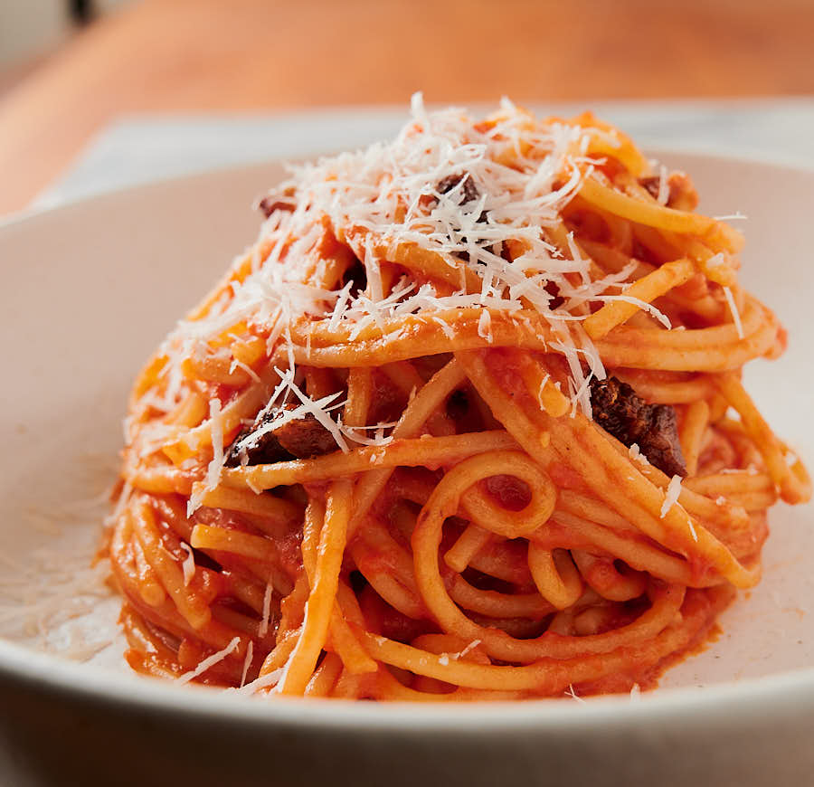 Plated mound of spaghetti all'amatriciana in a white bowl