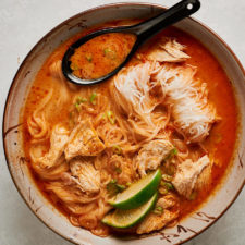 Bowl of tom kha gai noodle soup with a spoon