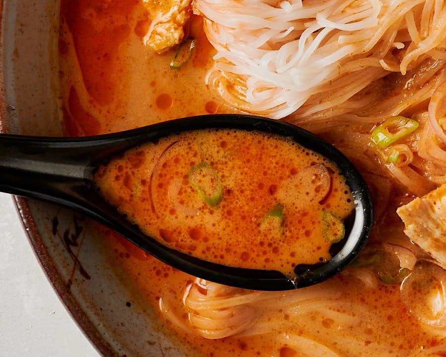 Closeup of red broth in a black spoon